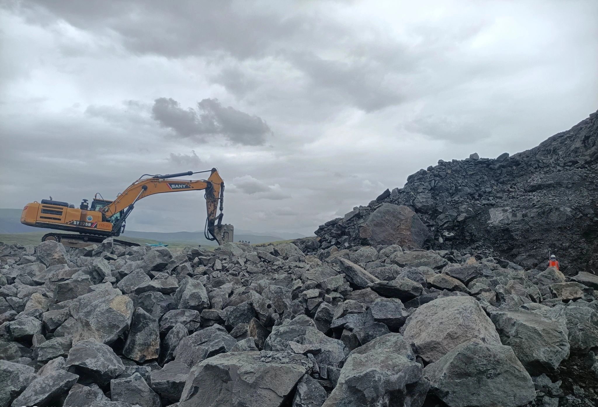 An excavator working on a rock face at an open-pit mine