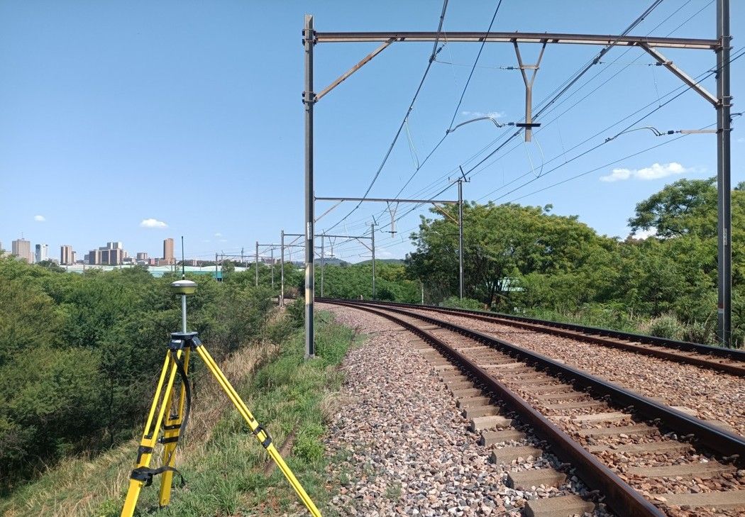 A survey instrument on a tripod next to a railway line