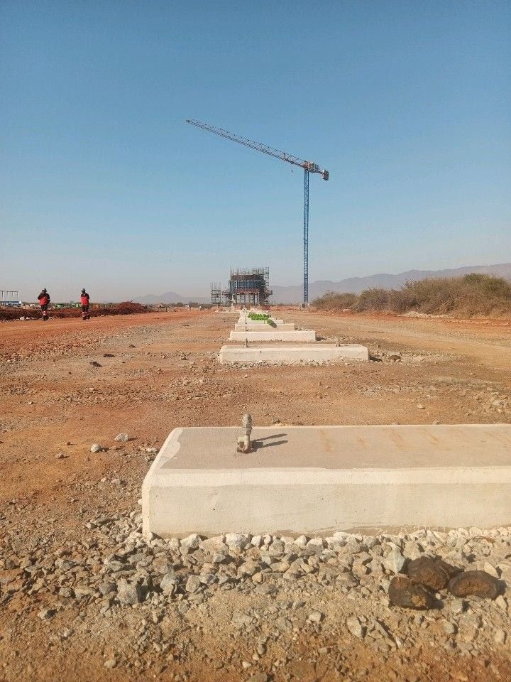 A line of concrete plinths with a tower crane in the distance