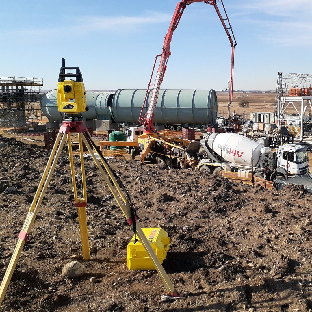 A total station on a construction site with a concrete pump behind it