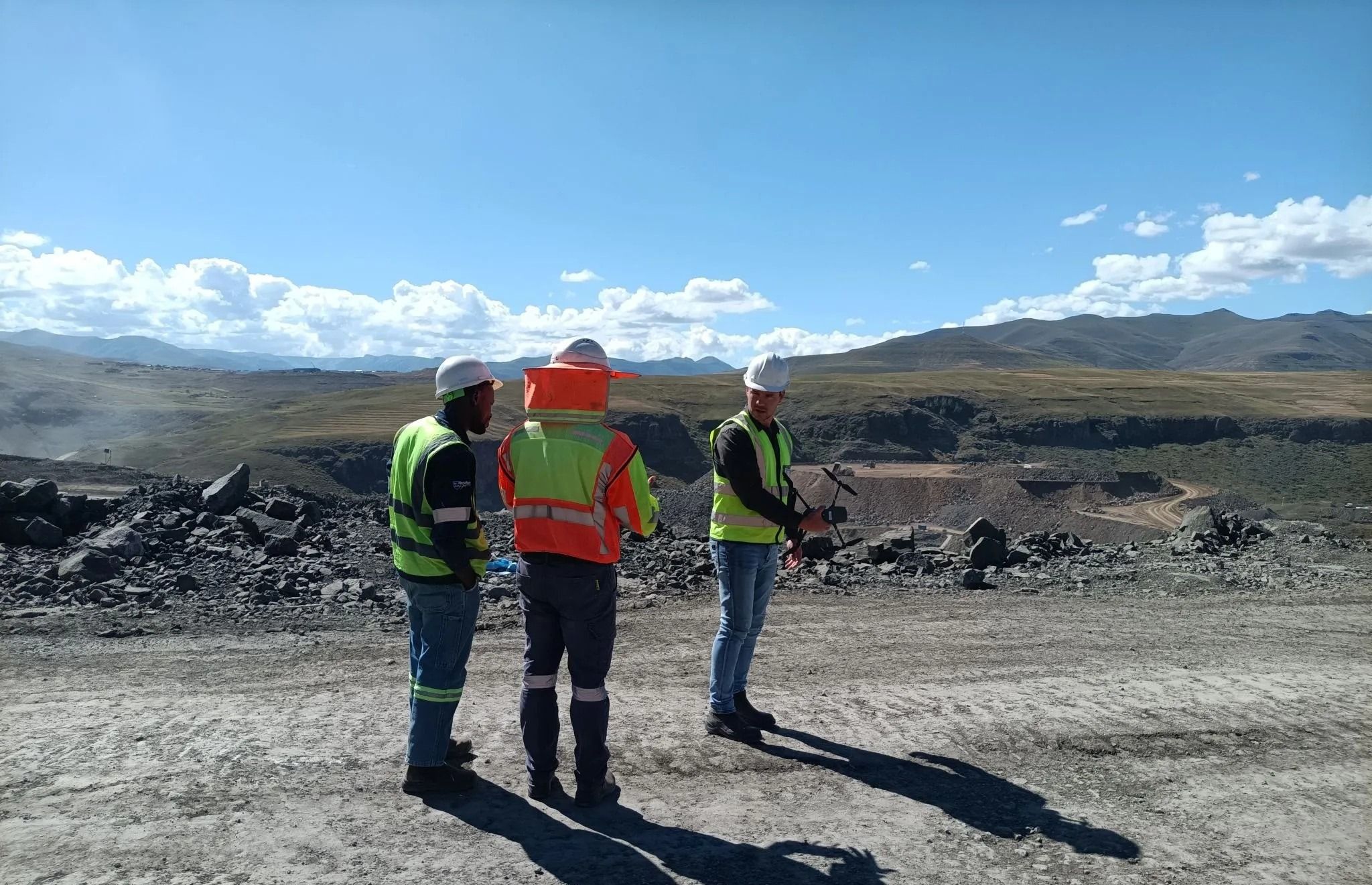 Three surveyors in hi-vis vests talking on a mine site