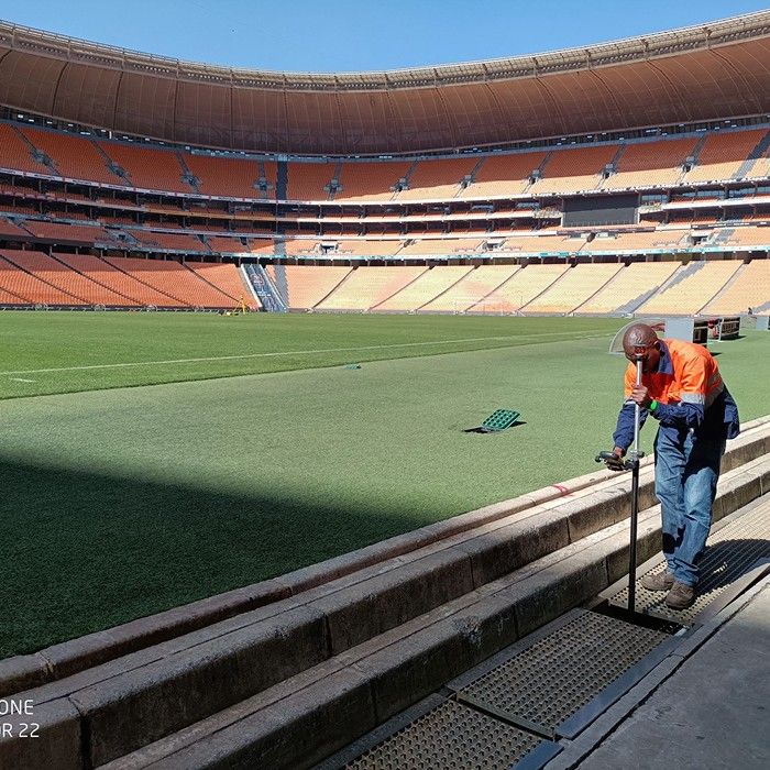 A surveyor measuring at the edge of the pitch