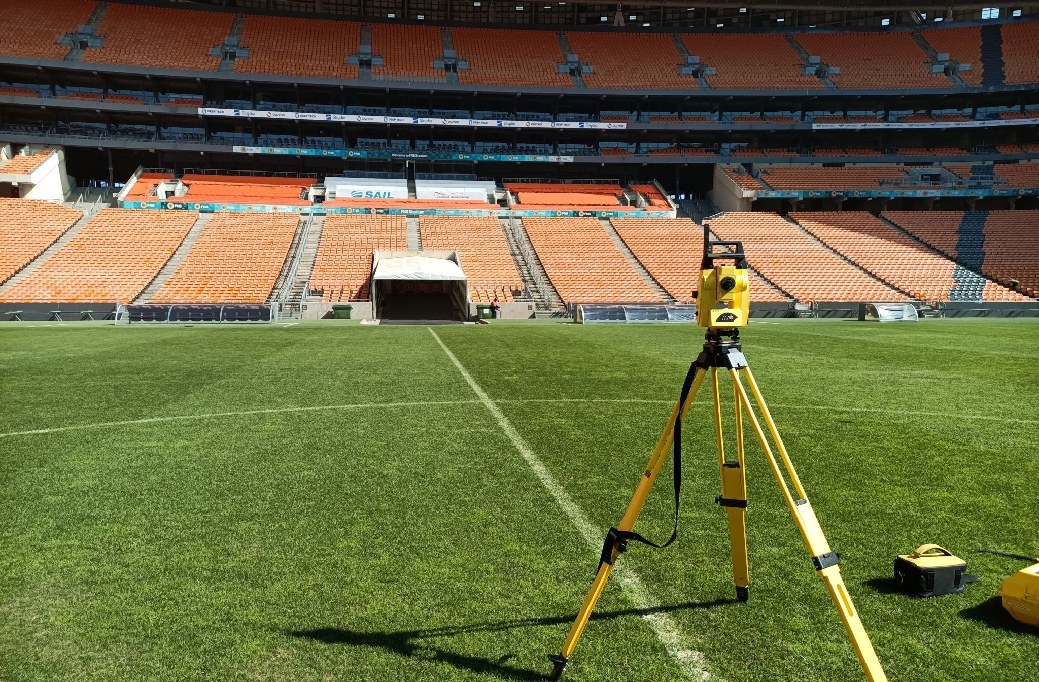 A total station on a yellow tripod on the pitch at FNB Stadium