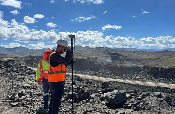 A surveyor with a GNSS rover at the edge of an open pit