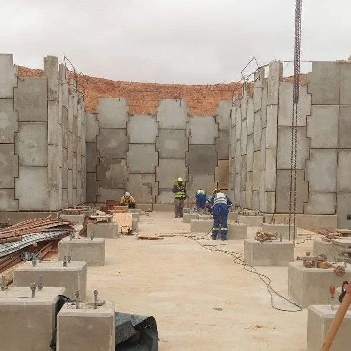 Workers at the foot of an interlocking precast wall