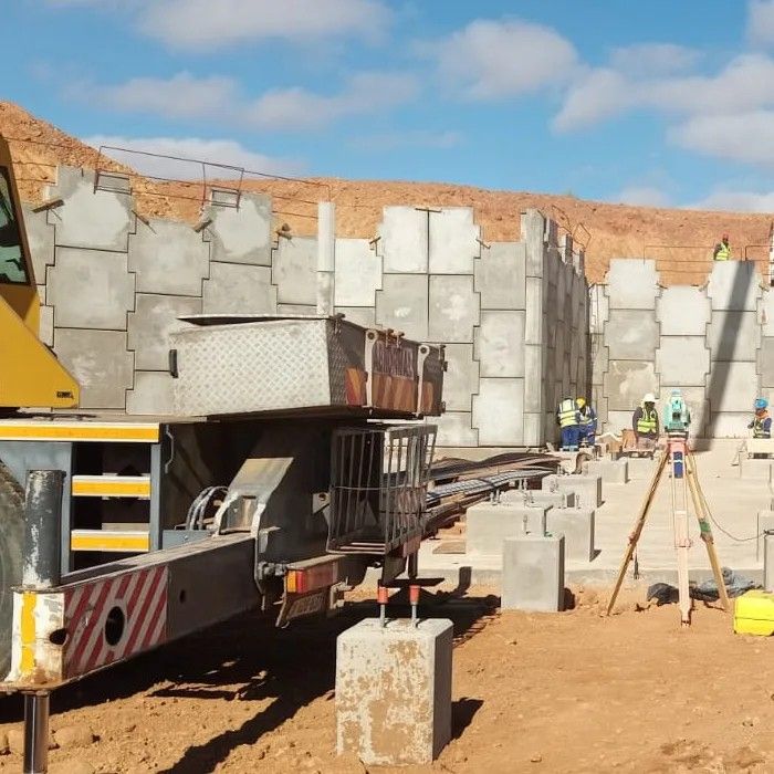 A low-bed truck delivering precast blocks to the wall