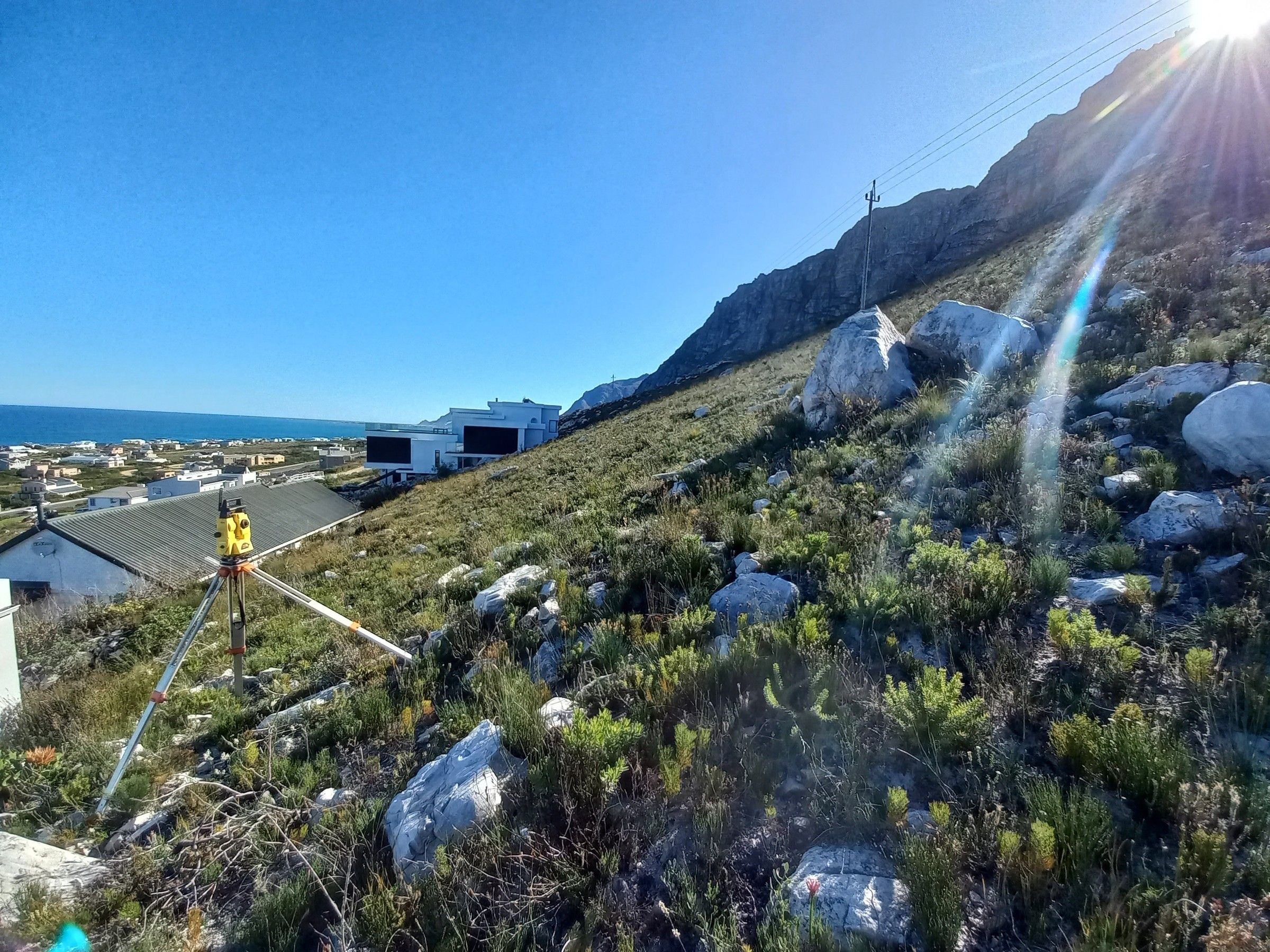 A survey instrument on a rocky hillside above the coast