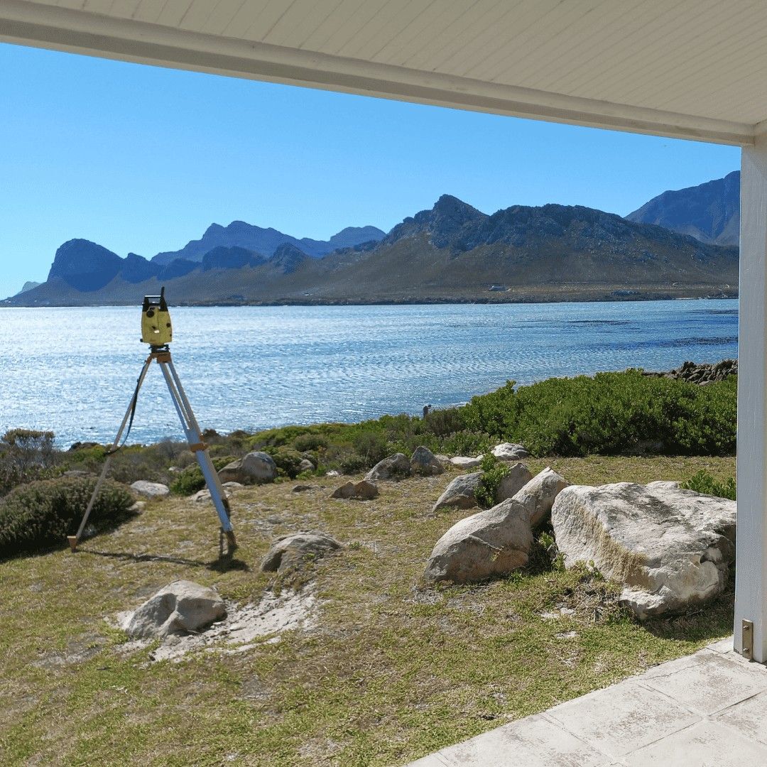 A survey instrument set up on the coast, with mountains across the bay