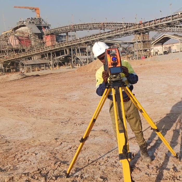 A surveyor sighting through a total station at the Lumwana plant