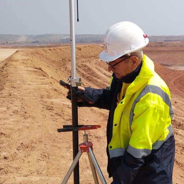 A surveyor in a hard hat reading a GNSS controller