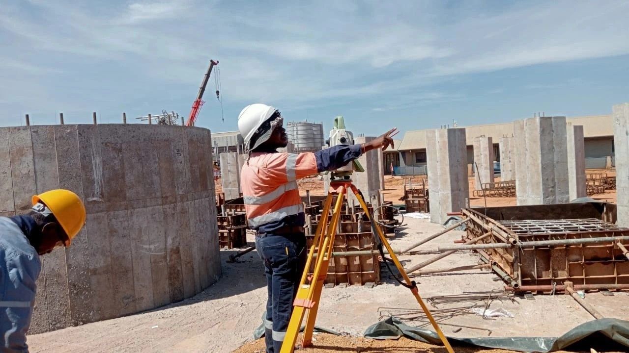 A surveyor with a total station at concrete works on a mine plant
