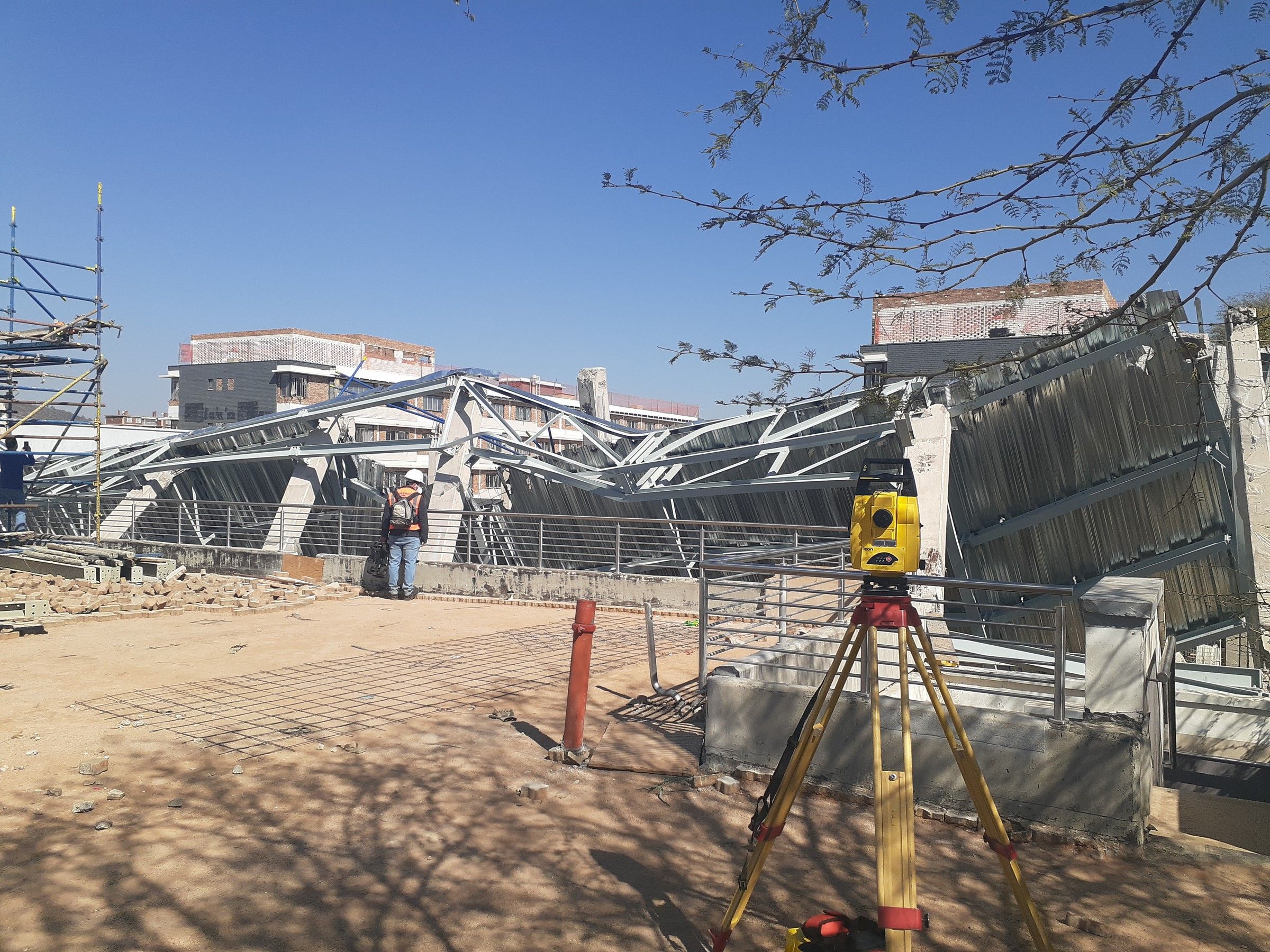A total station set up in front of a collapsed structure