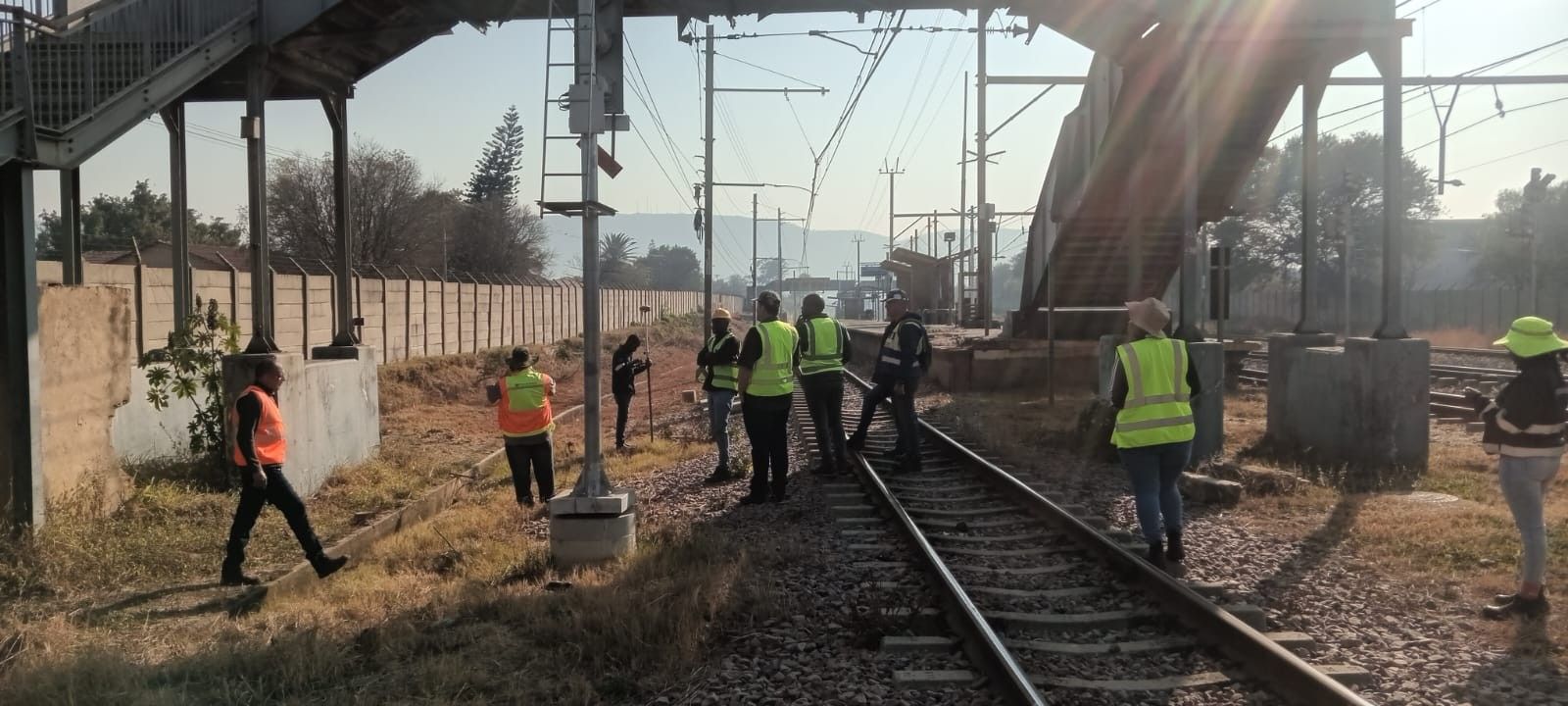 A survey crew in hi-vis vests working next to a railway line