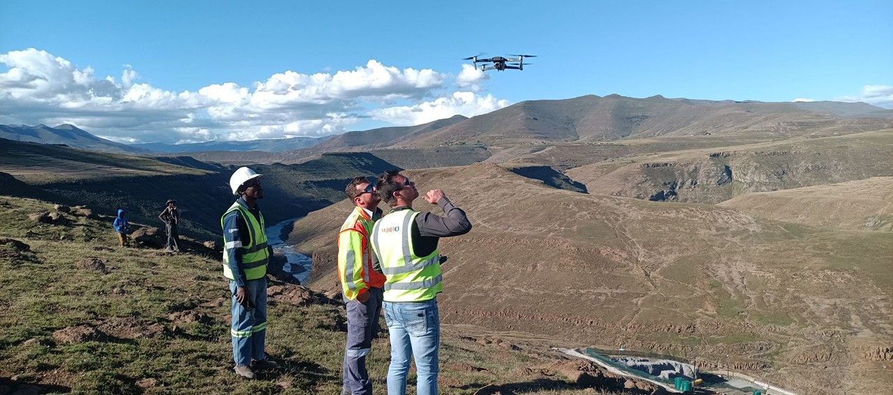 Three surveyors flying a drone over a valley
