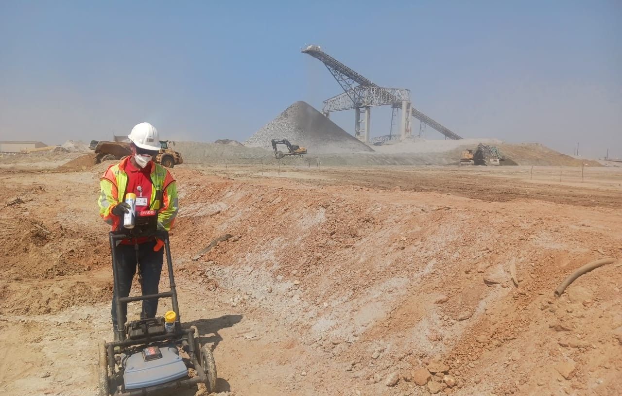 A surveyor pushing a ground penetrating radar cart across a site
