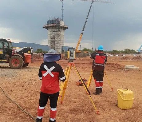 Three surveyors working around a total station on a construction site